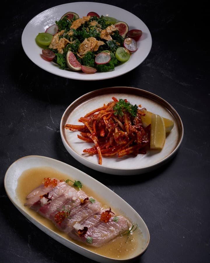 A selection of Korean dishes including pork, veg and fig salad