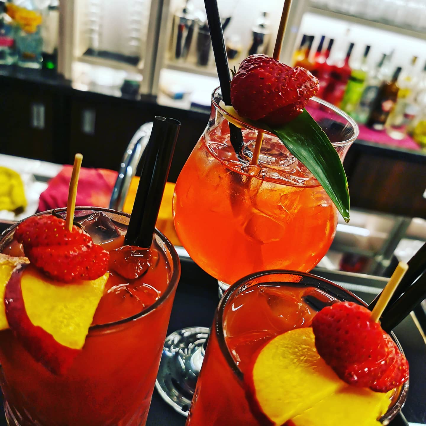 an aperol spritz and two strawberry cocktails in glasses on the bar of bar cavana one of the best bars in trieste italy