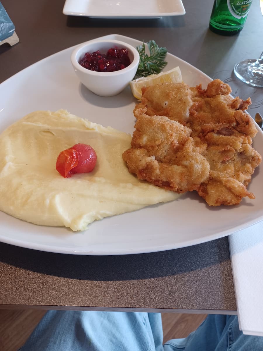 schnitzel weiner art with mashed potatoes and a cherry tomato on a white plate at kavarna park restaurant in bled slovenia