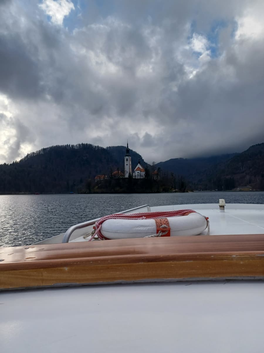 view of bled island church on an electric pletna boat crossing lake bled slovenia