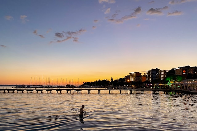 sunset over the adriatic as a man wades through the sea in portoroz slovenia