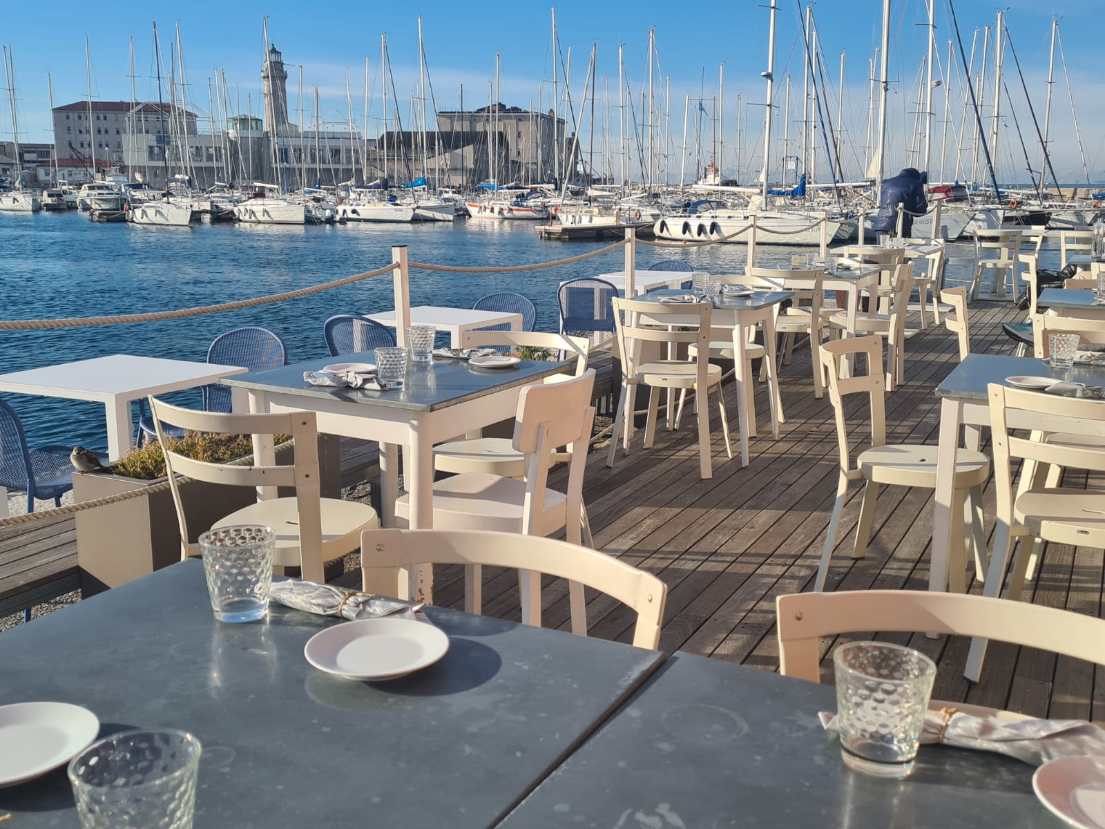tables on a wharf outside pier the roof restaurant over the gulf of trieste italy with sailing yachts in the background