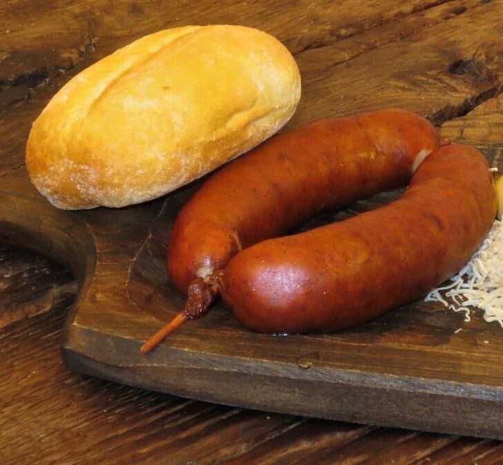 carniolan sausages are traditional slovenian foods served seen on a wooden board with a bread roll