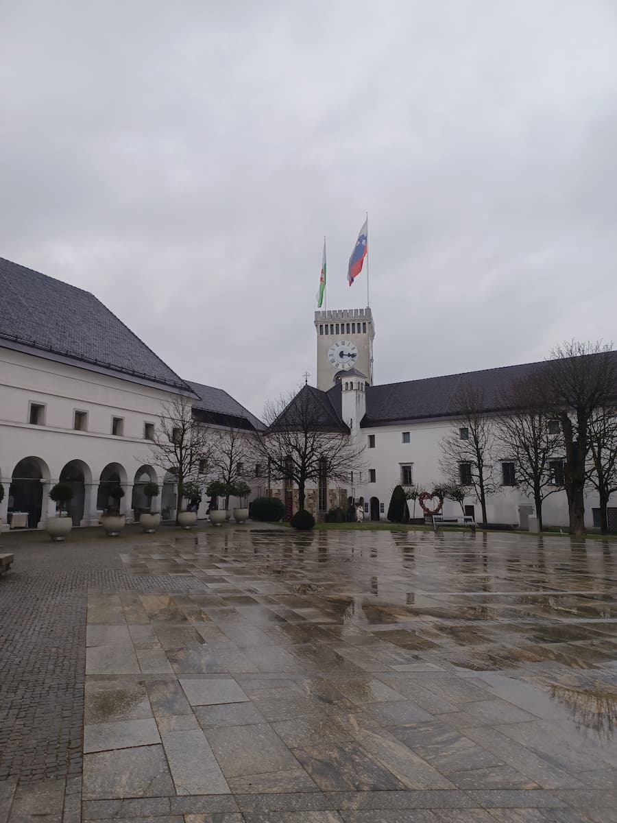 a slovenian flag on top of a white building in the courtyard of ljubljana castle