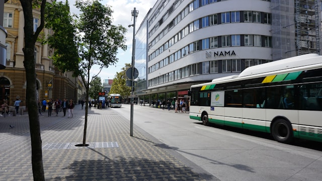 two buses on a road in front of a tall building in ljubljana slovenia