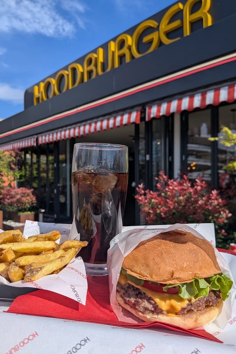 a burger with skin-on fries and a carbonated drink outside a hood burger fast-food restaurant in ljubljana slovenia
