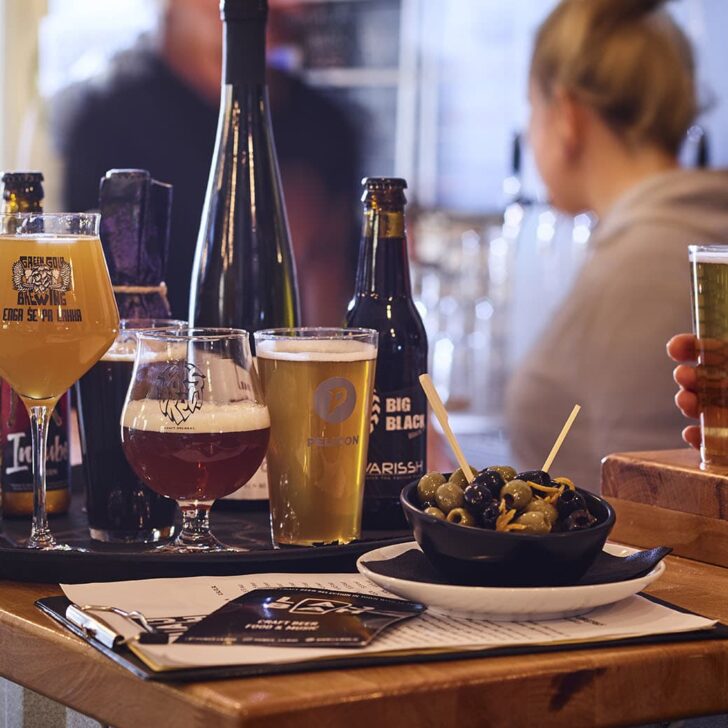 a trio of beer glasses on a black tray on top of a wooden bar at house of beer pub in ljubljana slovenia