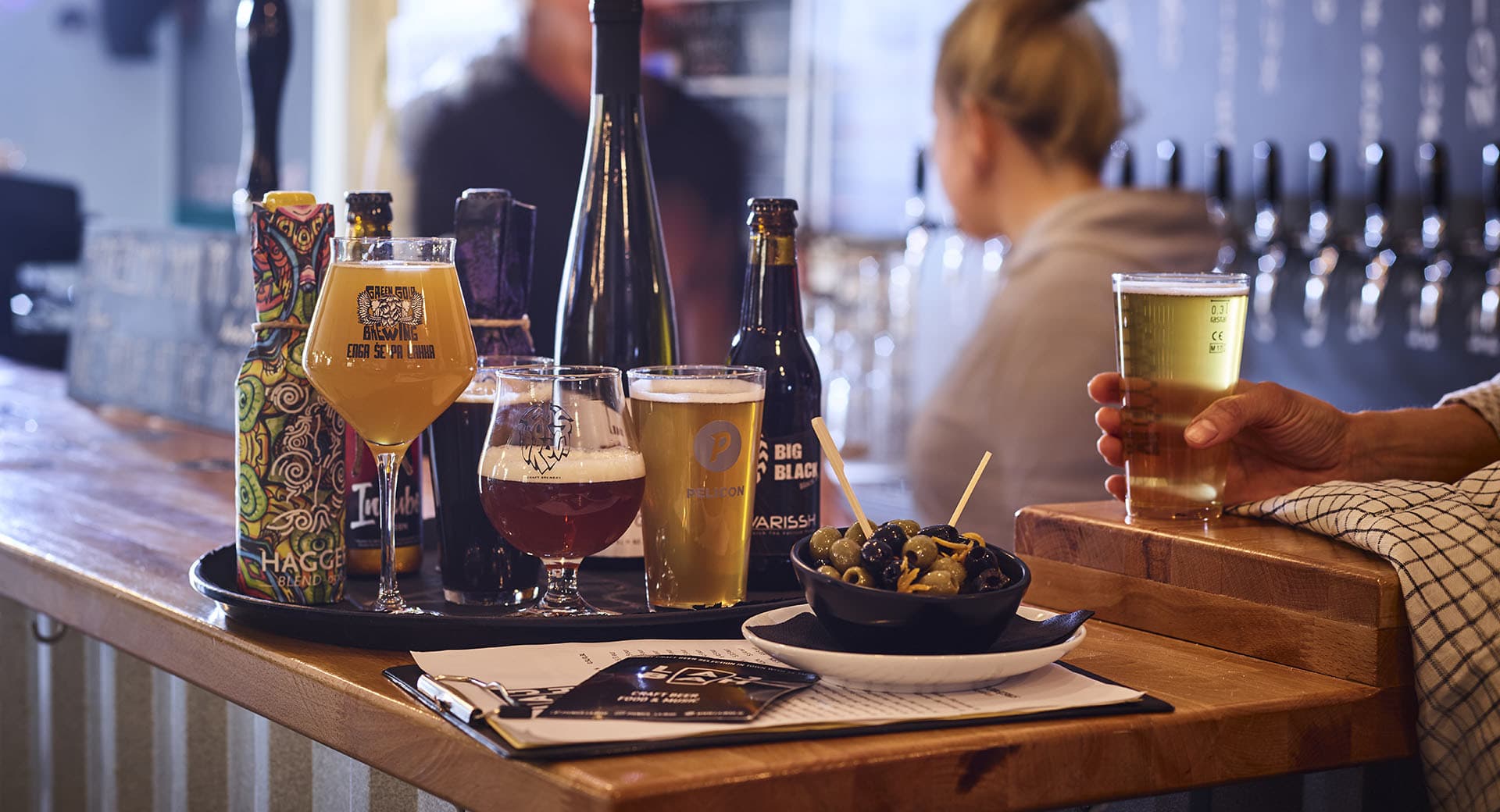 a trio of beer glasses on a black tray on top of a wooden bar at house of beer pub in ljubljana slovenia