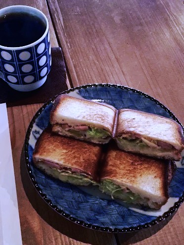 Plate of sandwiches next to a mug of black coffee in Kyoto Japan